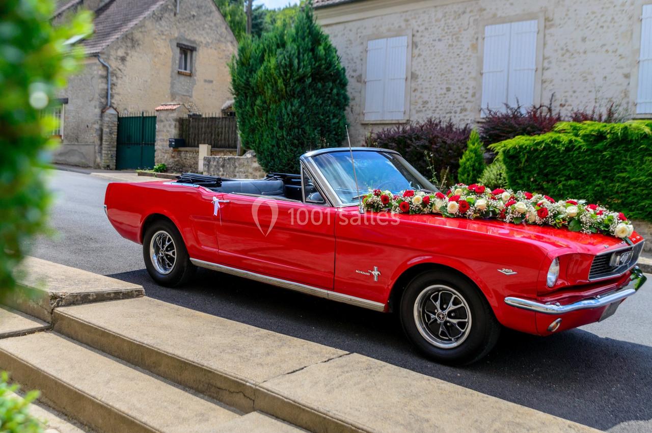 Voiture décapotable rouge ornée de fleurs blanches et rouges, stationnée dans une rue résidentielle.