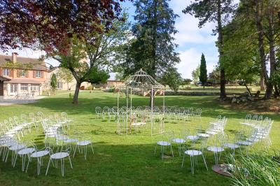 Train en bois pour enfants sur une pelouse, avec une tour en pierre et des arbres en arrière-plan au coucher du soleil.