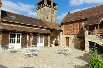Train en bois pour enfants sur une pelouse, avec une tour en pierre et des arbres en arrière-plan au coucher du soleil.