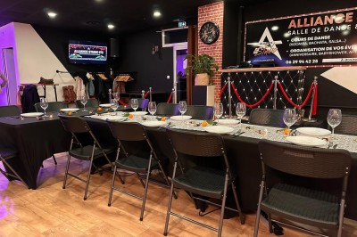 Table dressée avec vaisselle et décorations florales dans une salle de réception avec un comptoir et des affiches au mur.