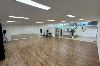 Salle lumineuse avec parquet, murs blancs, plantes décoratives et grandes fenêtres laissant entrer la lumière naturelle.