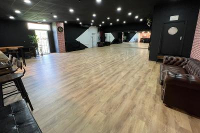 Salle lumineuse avec parquet, murs blancs, plantes décoratives et grandes fenêtres laissant entrer la lumière naturelle.