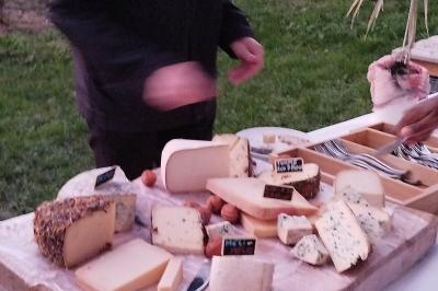 Espace extérieur couvert par une tente beige, avec des tables et des personnes assises dans un cadre verdoyant.