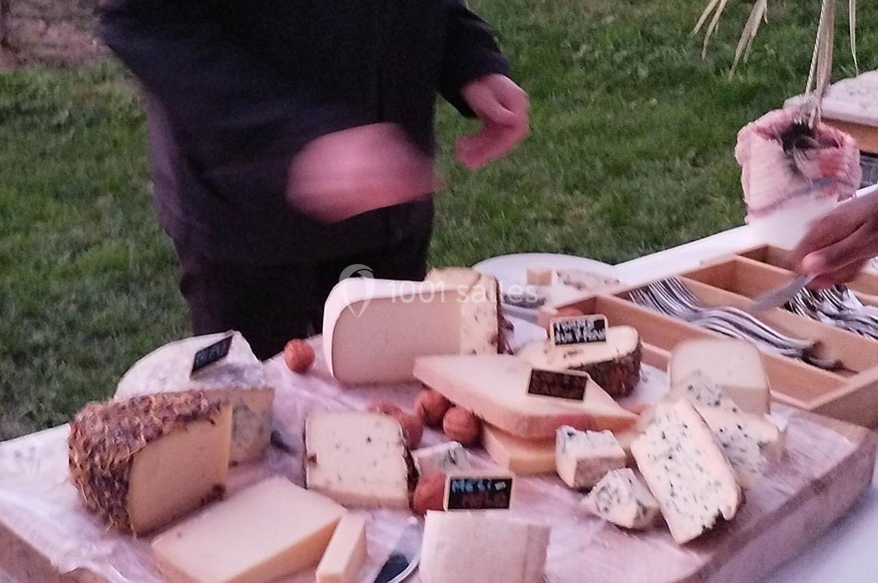 Plateau de fromages variés avec étiquettes, accompagné de noix, sur une table en extérieur.