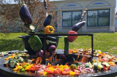 Espace extérieur couvert par une tente beige, avec des tables et des personnes assises dans un cadre verdoyant.