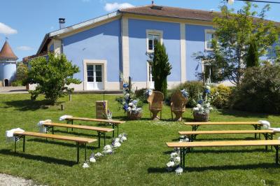 Espace extérieur couvert par une tente beige, avec des tables et des personnes assises dans un cadre verdoyant.