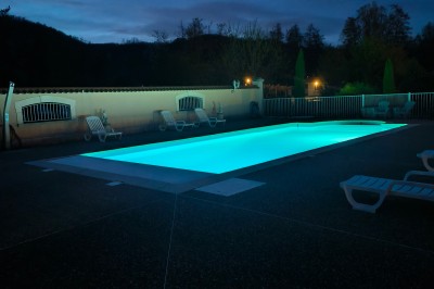 Espace extérieur couvert par une tente beige, avec des tables et des personnes assises dans un cadre verdoyant.