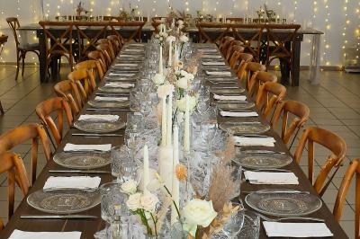 Centre de table floral avec roses blanches, feuillage et bougies blanches, sur une table de réception décorée en bleu et…