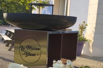 Centre de table floral avec roses blanches, feuillage et bougies blanches, sur une table de réception décorée en bleu et…