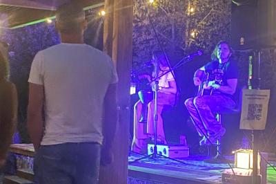 Centre de table floral avec roses blanches, feuillage et bougies blanches, sur une table de réception décorée en bleu et…