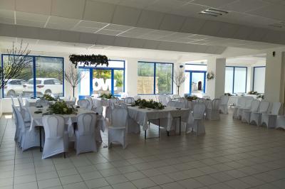 Centre de table floral avec roses blanches, feuillage et bougies blanches, sur une table de réception décorée en bleu et…