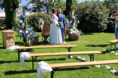 Centre de table floral avec roses blanches, feuillage et bougies blanches, sur une table de réception décorée en bleu et…