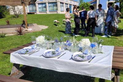 Centre de table floral avec roses blanches, feuillage et bougies blanches, sur une table de réception décorée en bleu et…