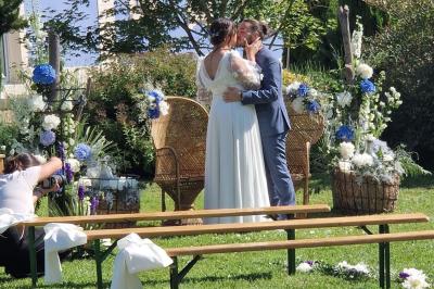 Centre de table floral avec roses blanches, feuillage et bougies blanches, sur une table de réception décorée en bleu et…