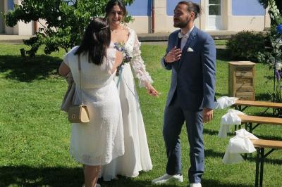 Centre de table floral avec roses blanches, feuillage et bougies blanches, sur une table de réception décorée en bleu et…