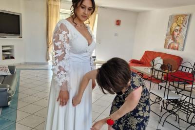 Centre de table floral avec roses blanches, feuillage et bougies blanches, sur une table de réception décorée en bleu et…