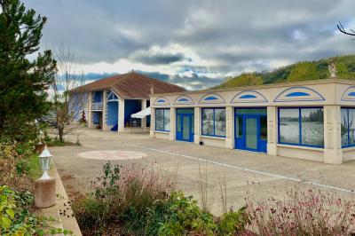Centre de table floral avec roses blanches, feuillage et bougies blanches, sur une table de réception décorée en bleu et…