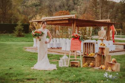 Centre de table floral avec roses blanches, feuillage et bougies blanches, sur une table de réception décorée en bleu et…