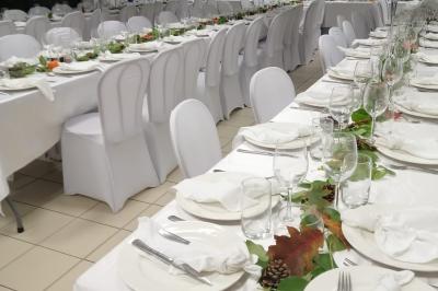 Centre de table floral avec roses blanches, feuillage et bougies blanches, sur une table de réception décorée en bleu et…