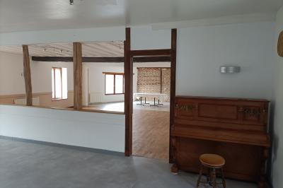 Un groupe de personnes assises et debout dans une salle avec des poutres apparentes, participant à une présentation.