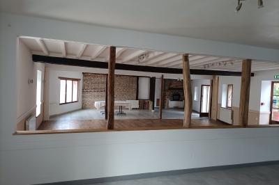 Un groupe de personnes assises et debout dans une salle avec des poutres apparentes, participant à une présentation.