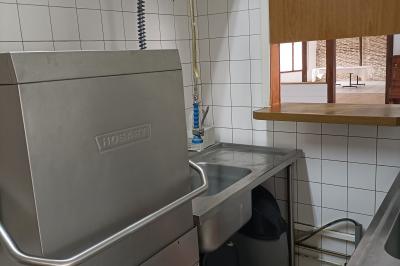 Un groupe de personnes assises et debout dans une salle avec des poutres apparentes, participant à une présentation.