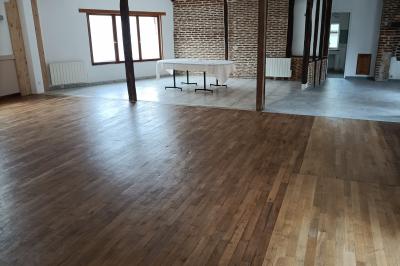 Un groupe de personnes assises et debout dans une salle avec des poutres apparentes, participant à une présentation.