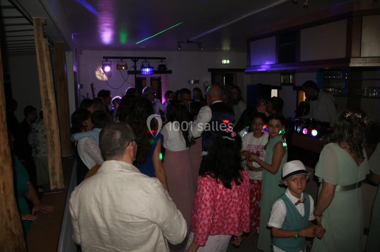 Groupe de personnes dans une salle sombre, éclairée par des lumières colorées, lors d'une fête ou d'un événement.