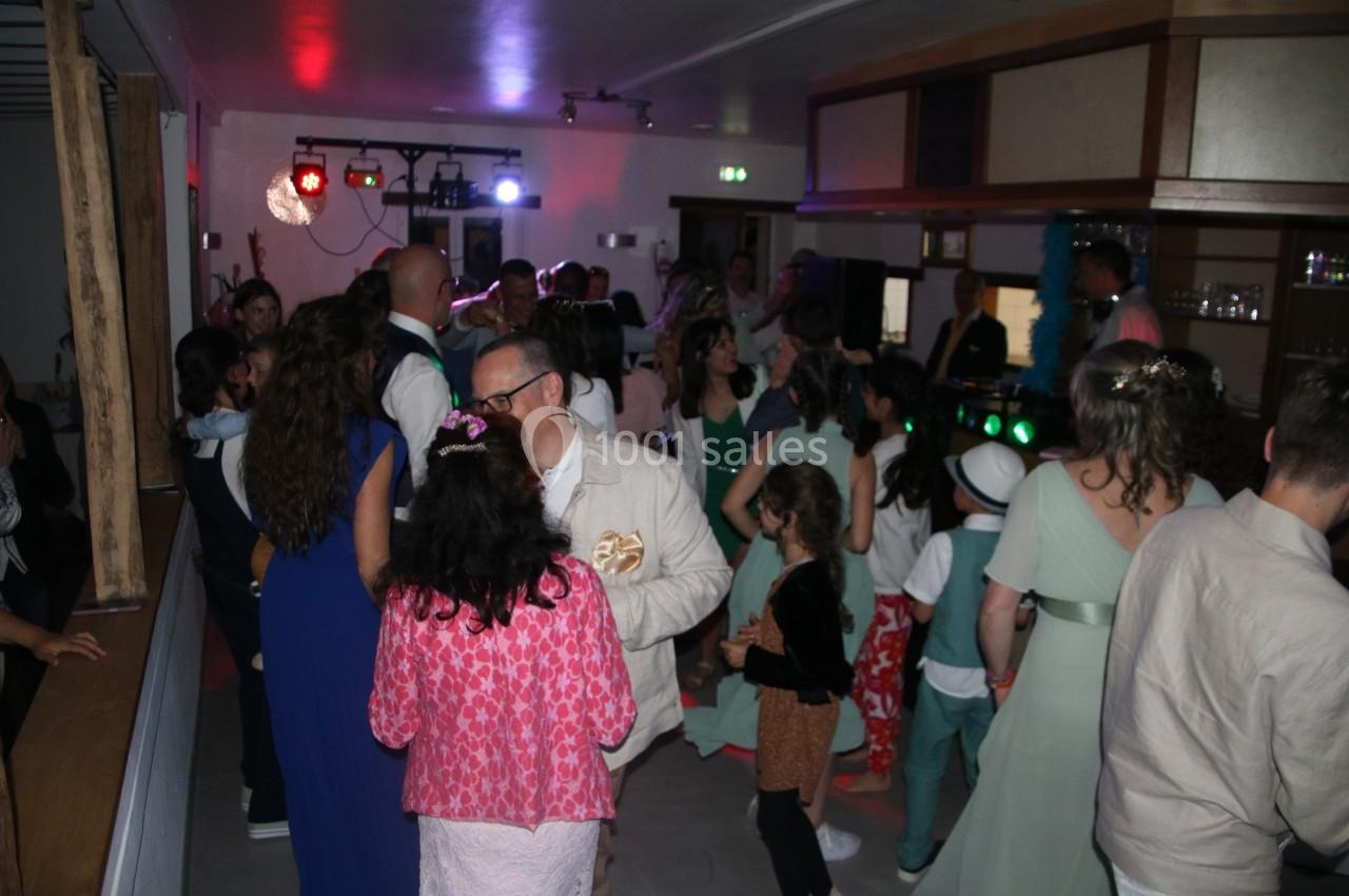 Groupe de personnes dans une salle éclairée par des lumières colorées, discutant et dansant lors d'un événement festif.