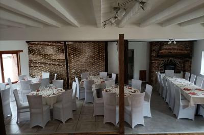 Un groupe de personnes assises et debout dans une salle avec des poutres apparentes, participant à une présentation.