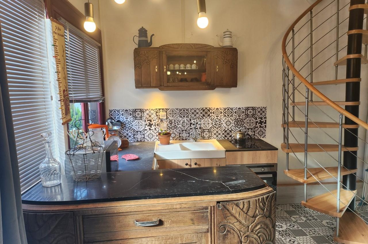 Cuisine avec meubles en bois sculpté, plan de travail en marbre, carrelage décoratif et escalier en colimaçon.