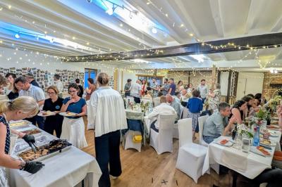 Un groupe de personnes assises et debout dans une salle avec des poutres apparentes, participant à une présentation.