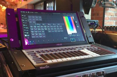Entrée d'un bâtiment en briques avec porte ouverte, escaliers, pots de fleurs et haut-parleurs disposés de chaque côté.