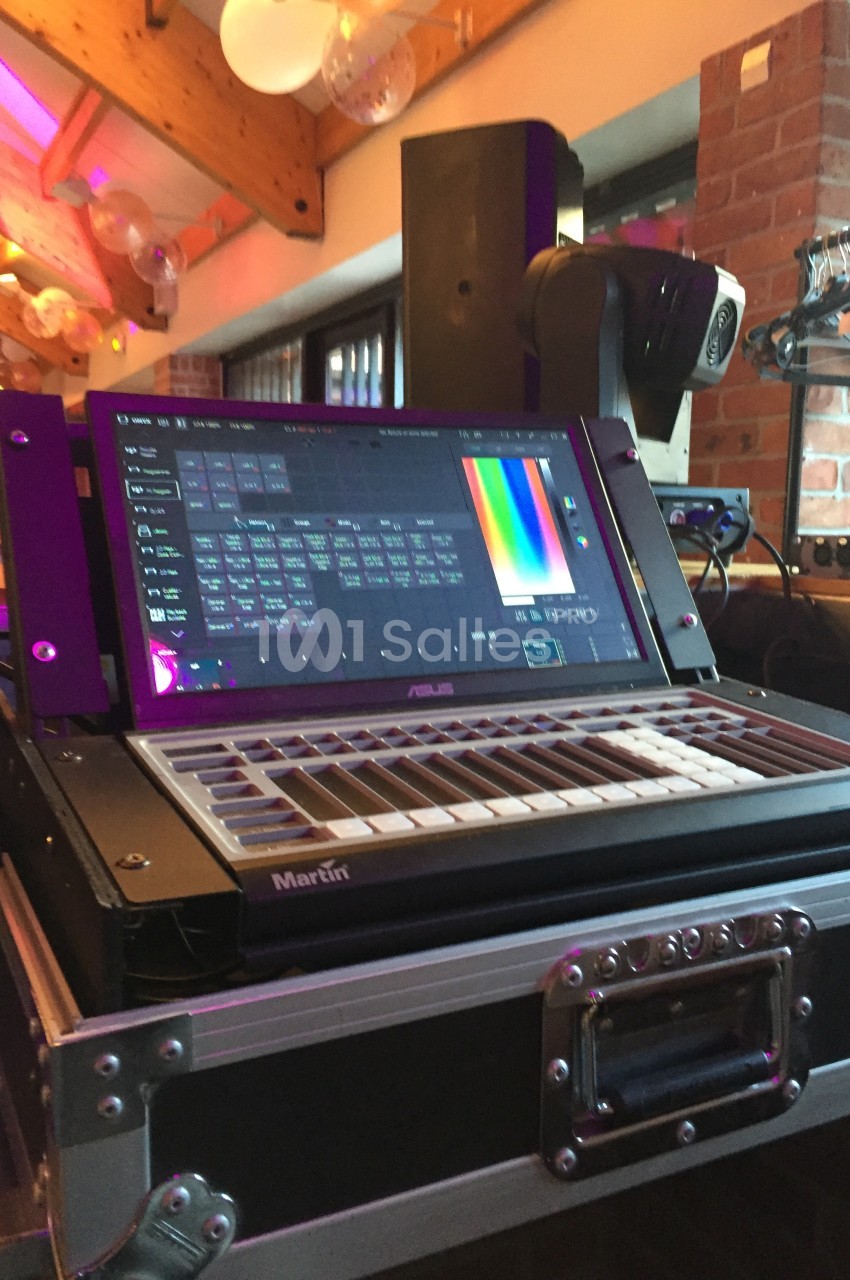 Console de contrôle d'éclairage avec écran tactile affichant des réglages colorimétriques, installée dans un espace…