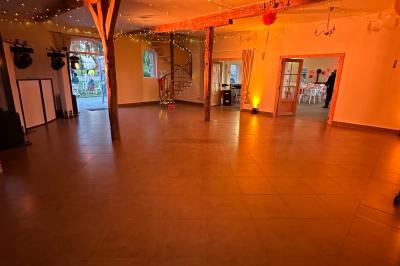 Entrée d'un bâtiment en briques avec porte ouverte, escaliers, pots de fleurs et haut-parleurs disposés de chaque côté.