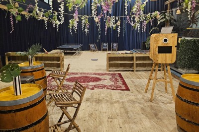 Comptoir en bois d'un bar à thème tropical avec tabourets pliants, éclairage en paille et décoration végétale.