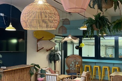 Comptoir en bois d'un bar à thème tropical avec tabourets pliants, éclairage en paille et décoration végétale.