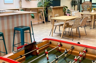 Comptoir en bois d'un bar à thème tropical avec tabourets pliants, éclairage en paille et décoration végétale.