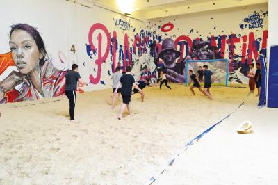 Comptoir en bois d'un bar à thème tropical avec tabourets pliants, éclairage en paille et décoration végétale.