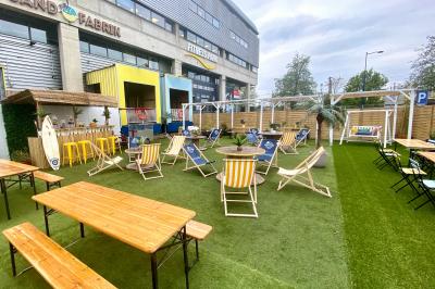 Des personnes participent à un jeu d'adresse avec des labyrinthes en bois dans un espace intérieur sur sol sablé.
