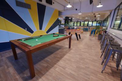 Des personnes participent à un jeu d'adresse avec des labyrinthes en bois dans un espace intérieur sur sol sablé.