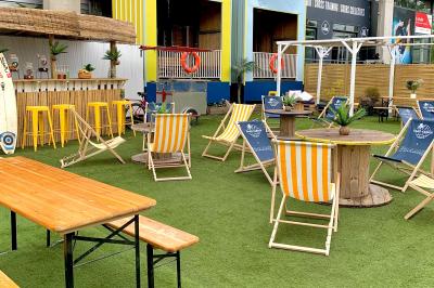 Des personnes participent à un jeu d'adresse avec des labyrinthes en bois dans un espace intérieur sur sol sablé.
