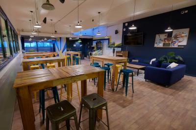 Des personnes participent à un jeu d'adresse avec des labyrinthes en bois dans un espace intérieur sur sol sablé.