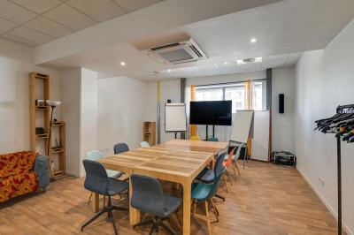 Des personnes participent à un jeu d'adresse avec des labyrinthes en bois dans un espace intérieur sur sol sablé.