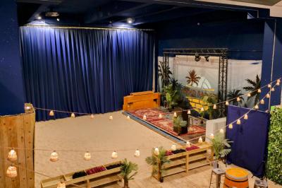 Des personnes participent à un jeu d'adresse avec des labyrinthes en bois dans un espace intérieur sur sol sablé.