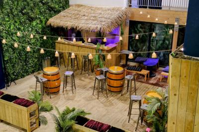 Des personnes participent à un jeu d'adresse avec des labyrinthes en bois dans un espace intérieur sur sol sablé.