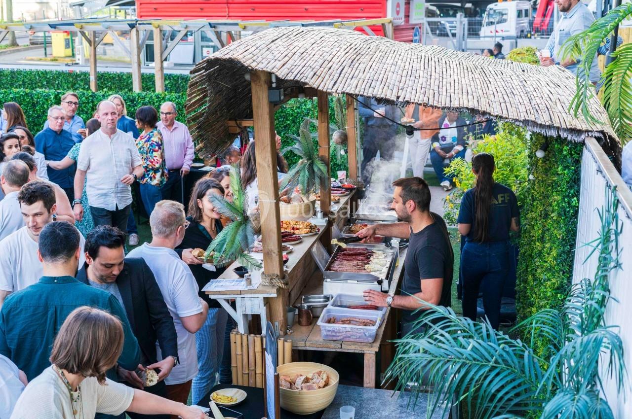 Stand de cuisine en plein air avec un cuisinier préparant des plats, entouré de personnes dans une ambiance conviviale.