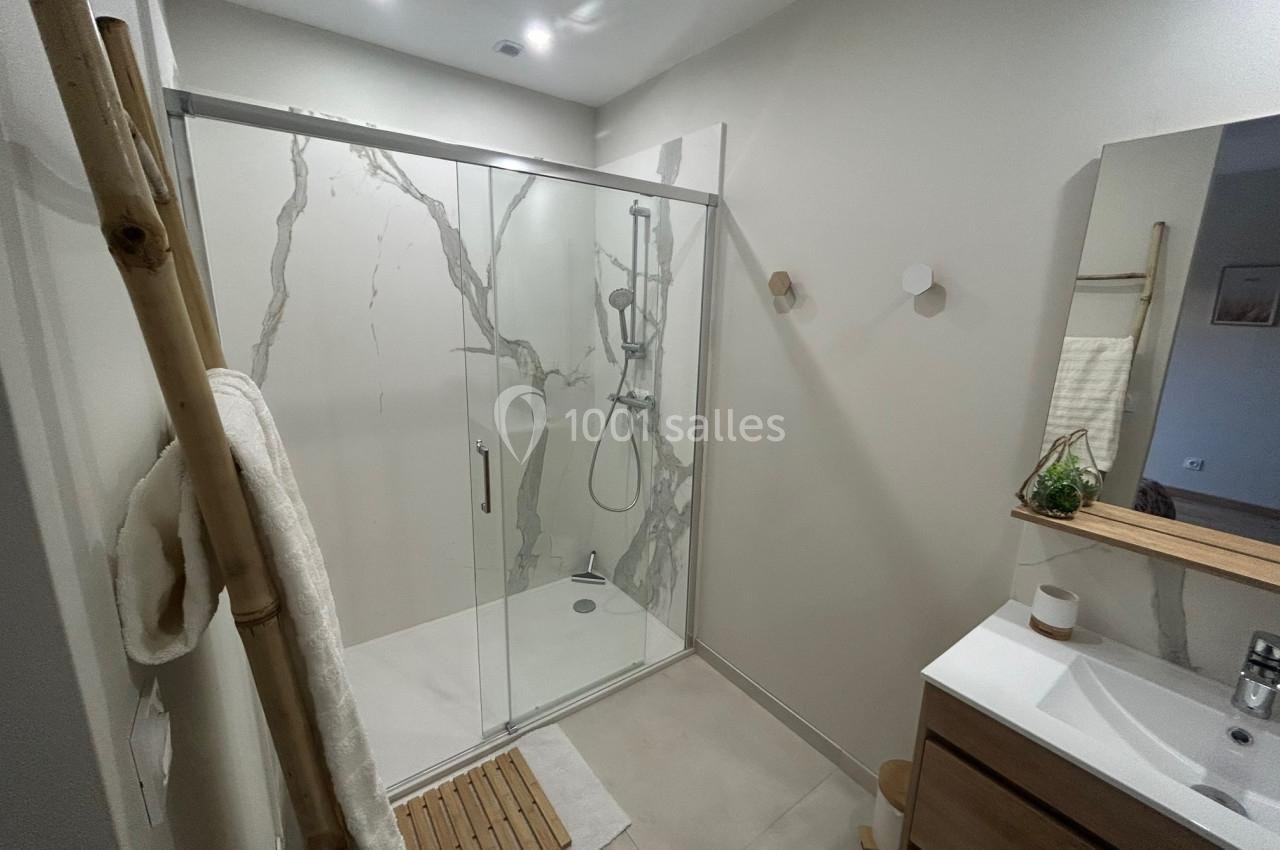 Salle de bain moderne avec douche à l'italienne, paroi en verre, meuble en bois et décoration minimaliste.