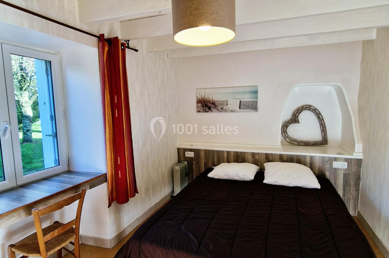 Chambre lumineuse avec lit double, bureau en bois près d'une fenêtre et décoration murale minimaliste.