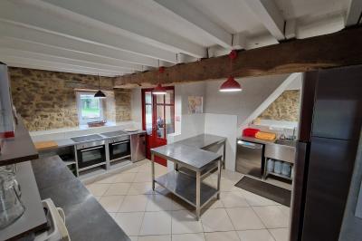 Deux lits avec couvertures bleues et marron dans une chambre lumineuse au sol en parquet et mur clair.